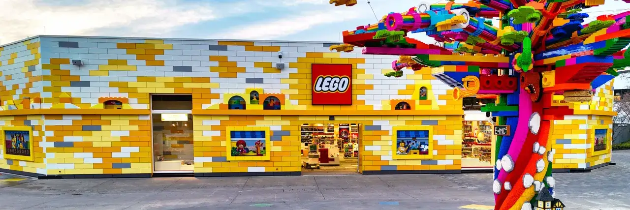 Buntes Geb&auml;ude im Stil eines Lego-Freizeitparks mit einem riesigen, bunten Lego-Baum davor.