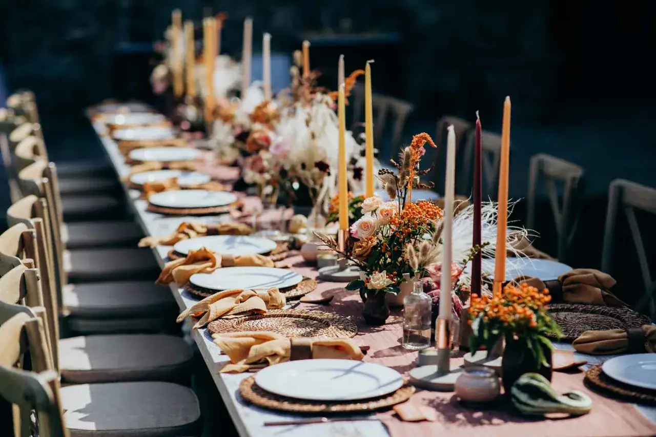 Festliche tischdeko hochzeit herbst mit Kerzen, Blumen und Stoffservietten in warmen Tönen.