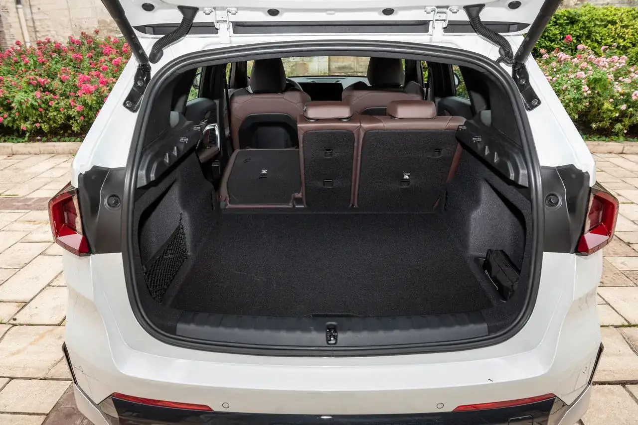 Vue arri&egrave;re du coffre d'une BMW X1, si&egrave;ges rabattus pour un essai. Espace de chargement spacieux.