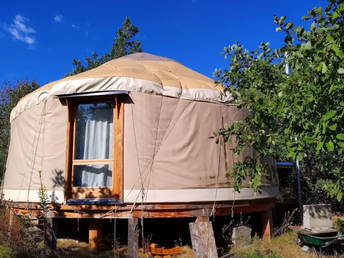 Une yourte d'h&ocirc;tes en Dordogne, perch&eacute;e sur pilotis, invite &agrave; la d&eacute;tente sous un ciel bleu.
