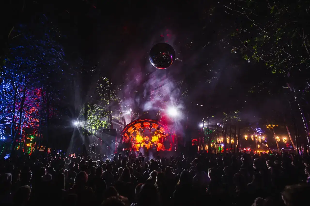 Nocny festiwal w lesie. Tłum ludzi bawi się przy scenie oświetlonej kolorowymi światłami. W powietrzu unosi się dym, a nad głowami wisi kula dyskotekowa. To musi być wspaniały wisloujscie lineup!