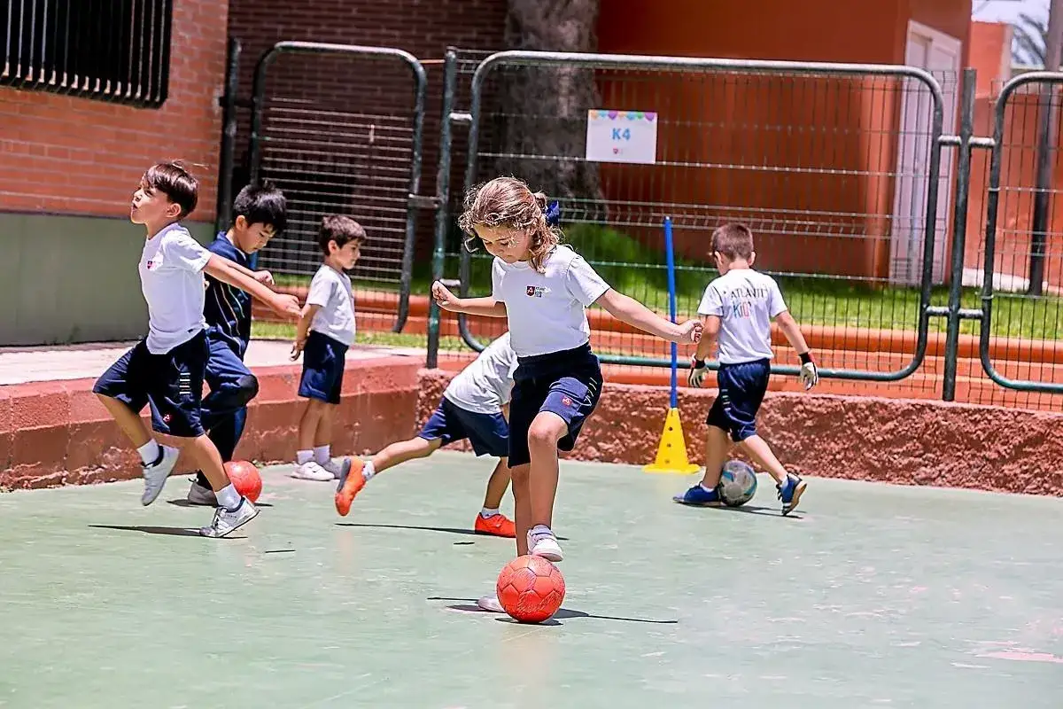 Niños jugando al fútbol como parte de sus actividades extraescolares. Se divierten en un patio de recreo.