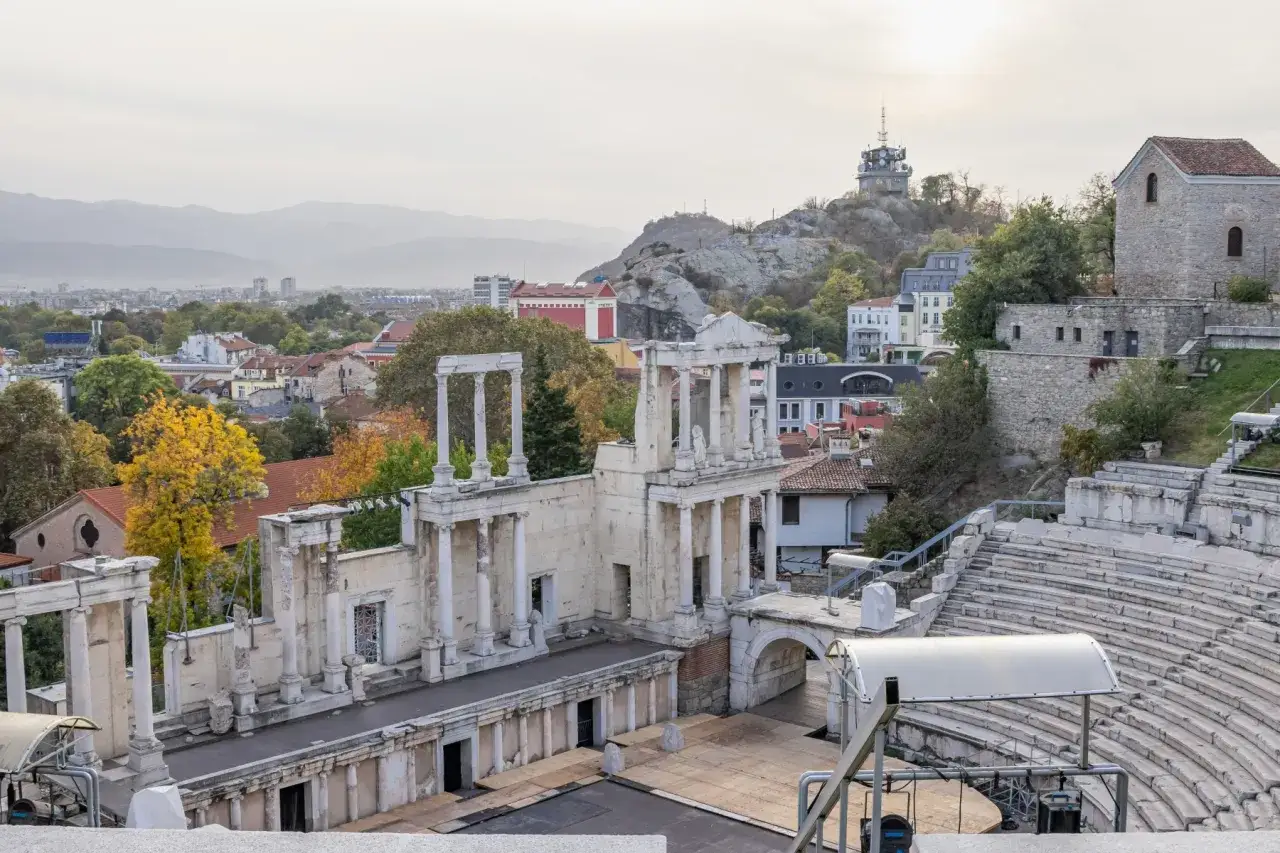 Starożytny teatr w Plovdiv, Bułgaria, z widokiem na miasto i wzgórze z wieżą.