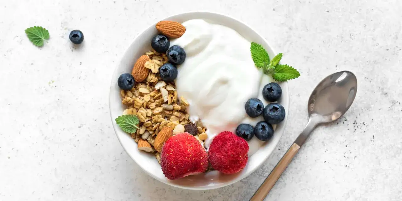 En sk&aring;l med grekisk yoghurt, granola, bl&aring;b&auml;r, jordgubbar och mandlar. En nyttig och god frukost.