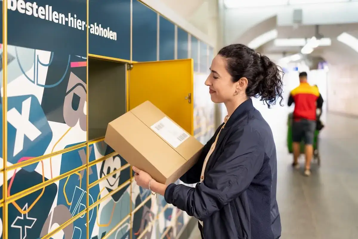 Frau holt Paket bei Paketstation ab.