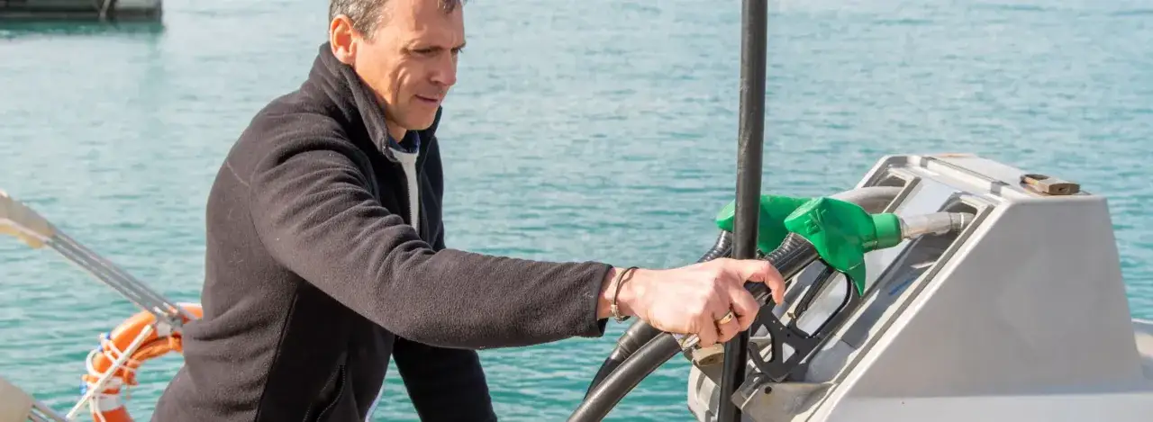 Uomo fa rifornimento alla barca, preoccupato per il costo gasolio nautico.