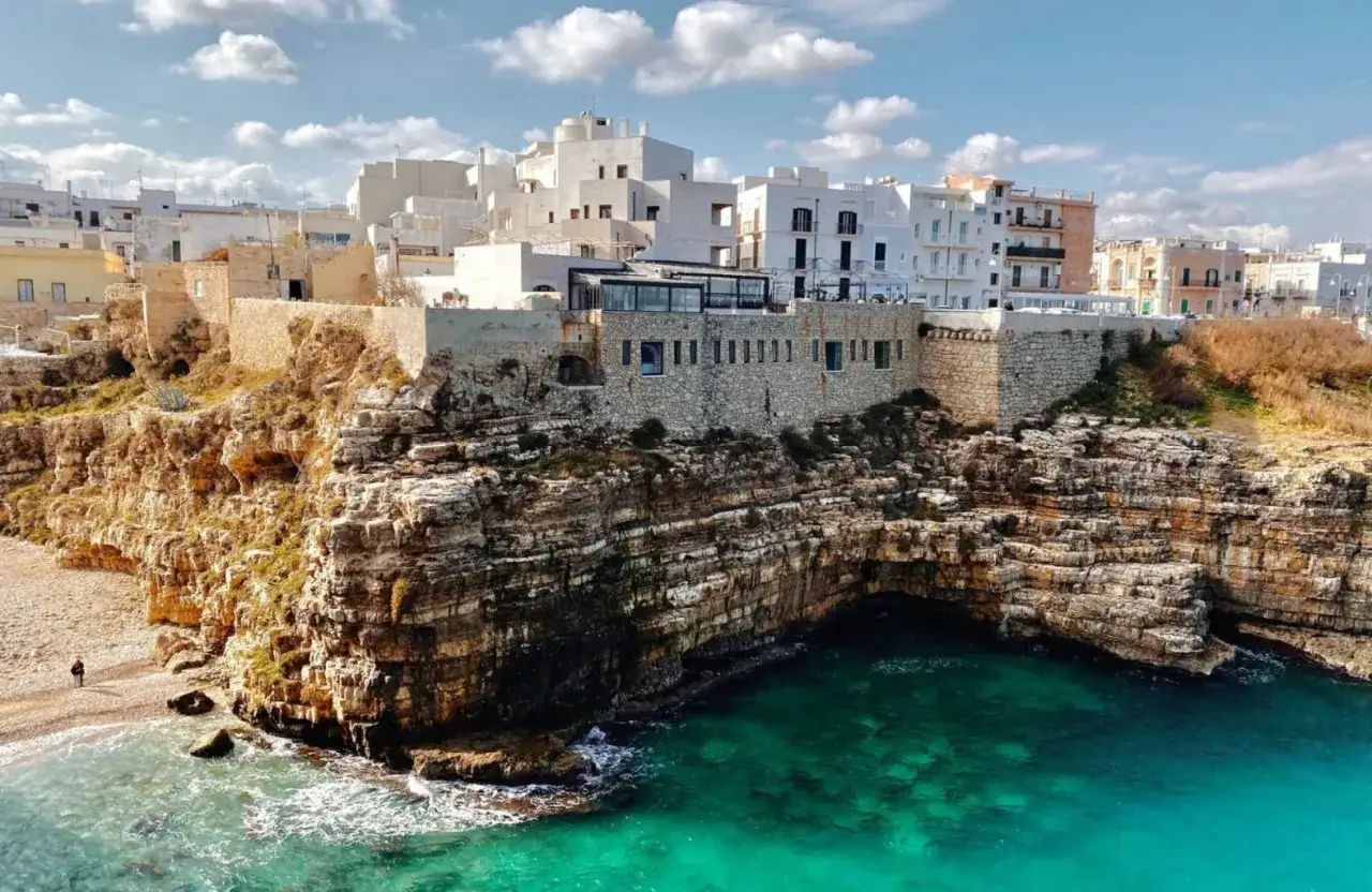 Scogliere mozzafiato e case bianche a picco sul mare turchese, perfetti **posti da visitare in Puglia estate**.