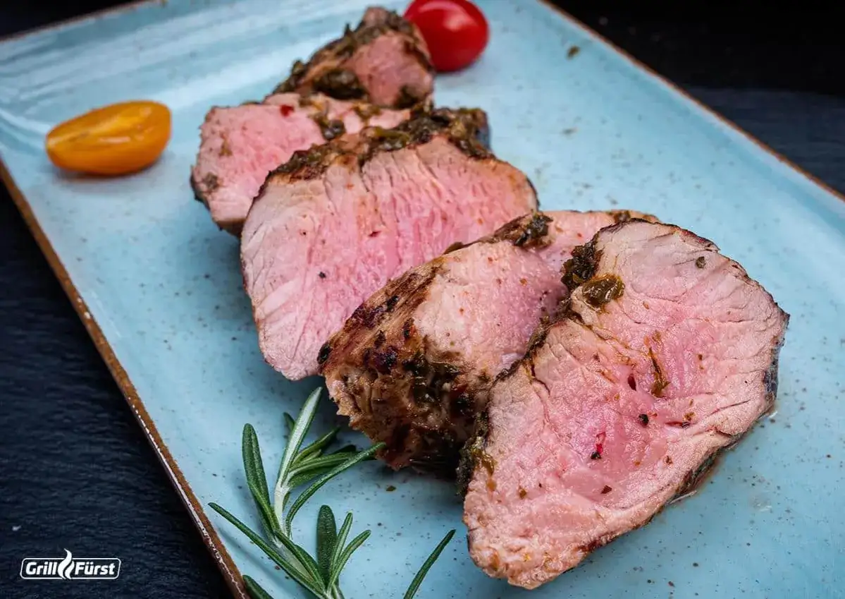 Saftige Scheiben von **Lende auf dem Grill**, garniert mit Rosmarin und Kirschtomaten. Perfekt gegrillt und zart.