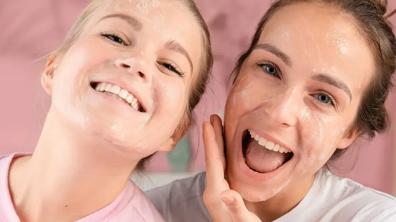 Zwei lachende Frauen mit Gesichtsmaske. Sie genie&szlig;en die nat&uuml;rliche Pflege f&uuml;r ihre Haut, um sie zu entgiften. Hausmittel f&uuml;r reine Haut.