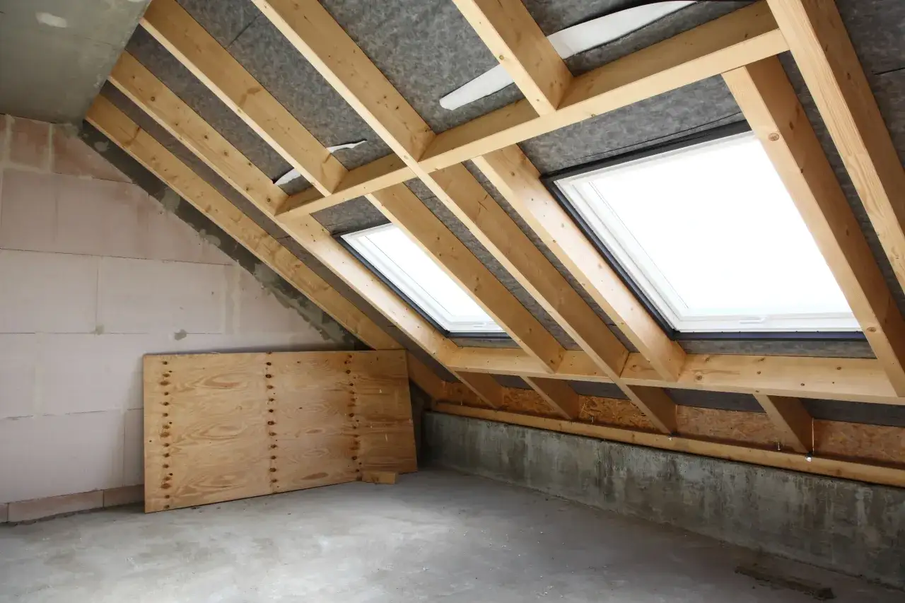 Charpente de toit en cours d'installation avec fenêtres de toit. Le chantier est prêt pour l'isolation, un élément clé pour le prix de l'isolation toiture.