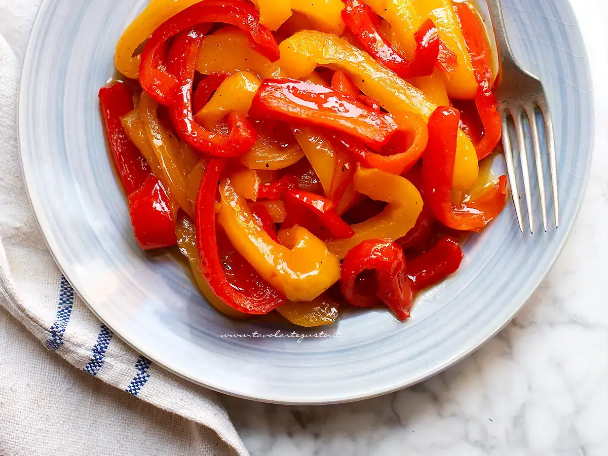 Piatto di peperoni rossi e gialli saltati, conditi con olio e spezie. Una deliziosa marmellata di peperoni pronta per essere gustata.