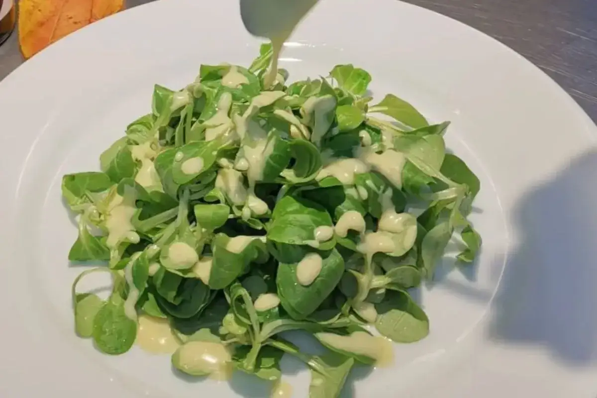 Frischer Feldsalat wird mit einem cremigen Kartoffeldressing beträufelt.