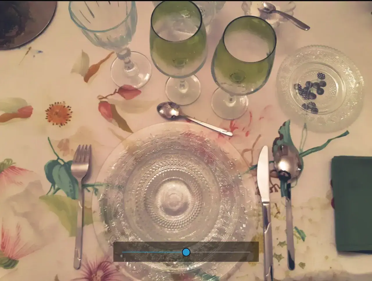 Mesa puesta con vajilla de cristal y copas verdes, evocando un elegante estilo francés.