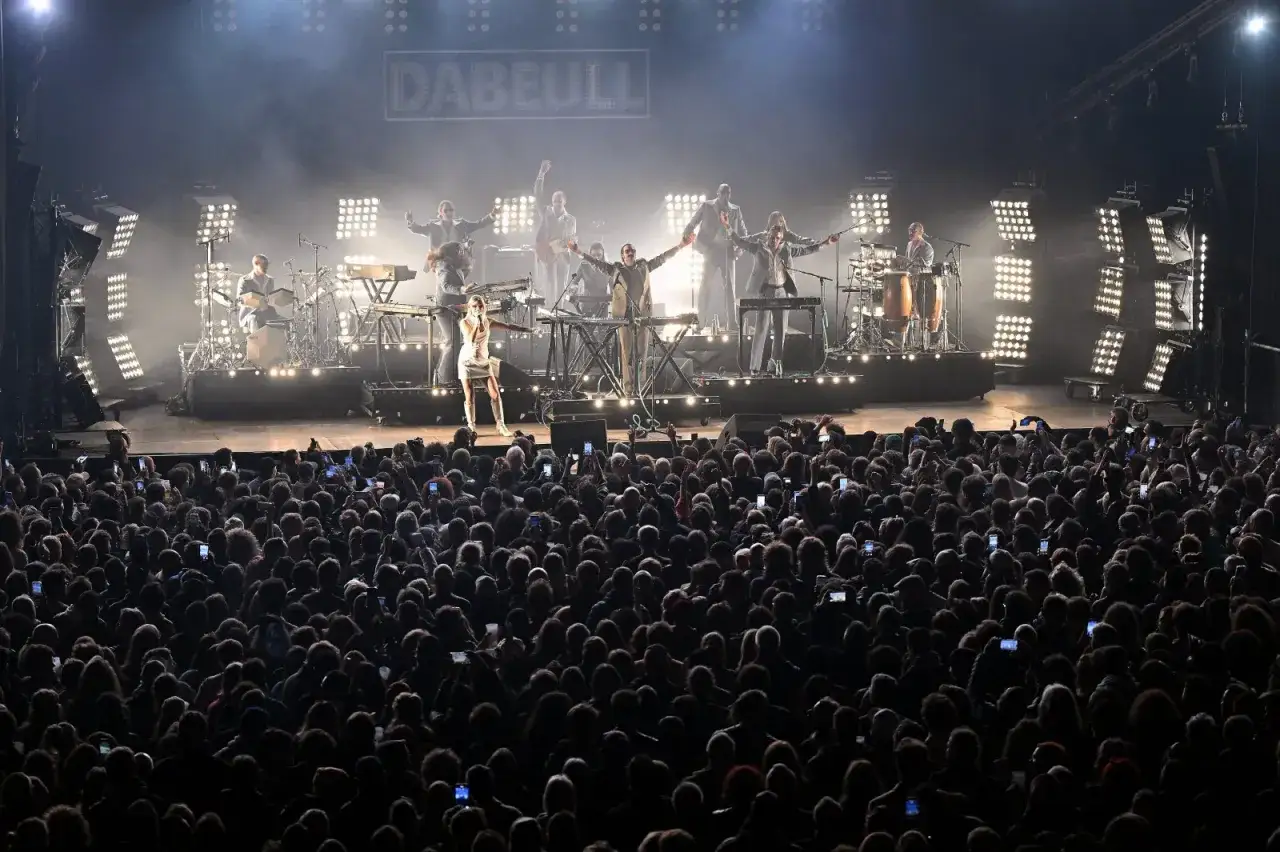 Le chanteur funk français Dabeull enflamme la scène devant une foule en délire, lumières éclatantes et fumée créant une ambiance électrique.