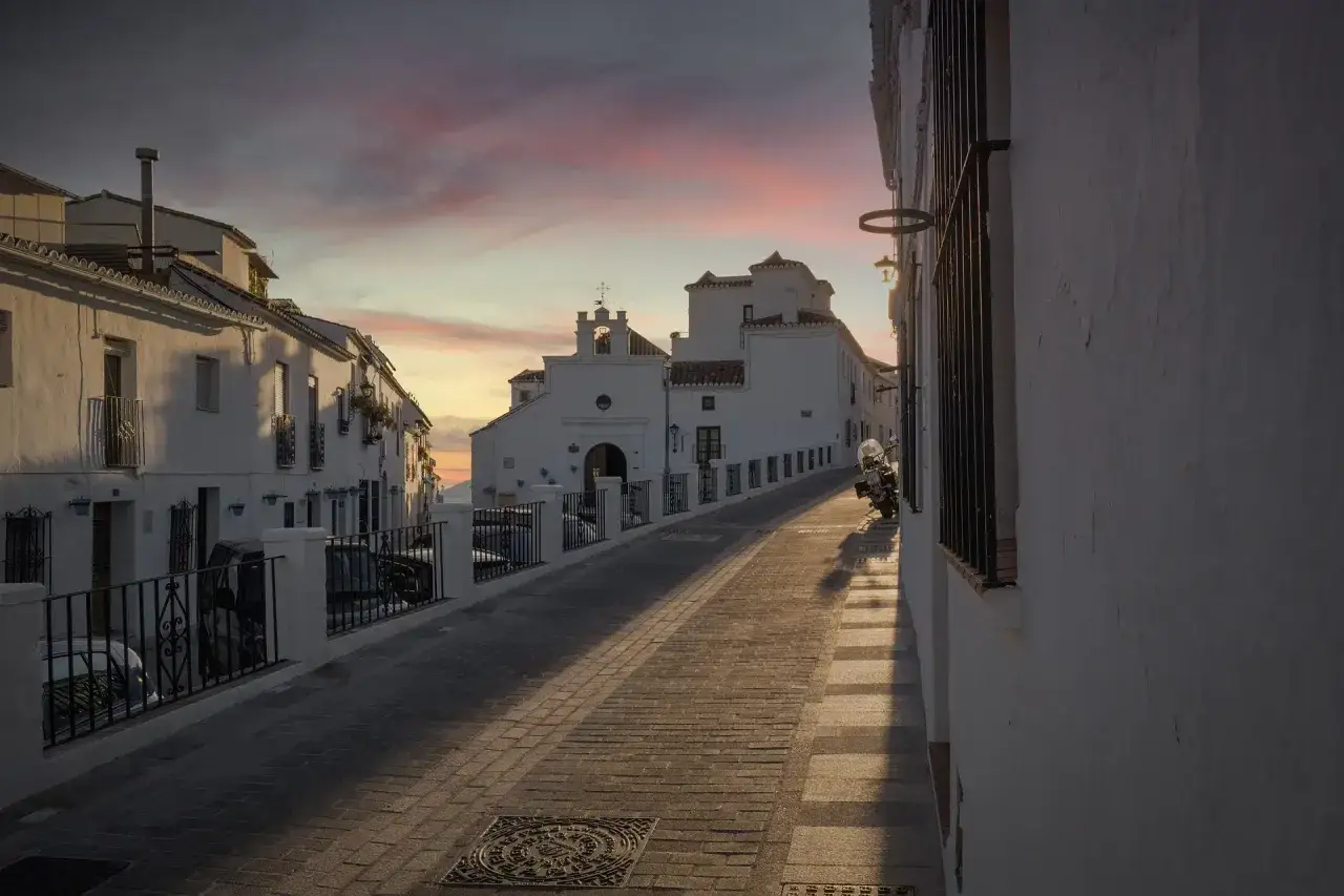 Atardecer en Mijas: calle empedrada, casas blancas y una iglesia. Ideal para saber qué ver en Mijas en una tarde.