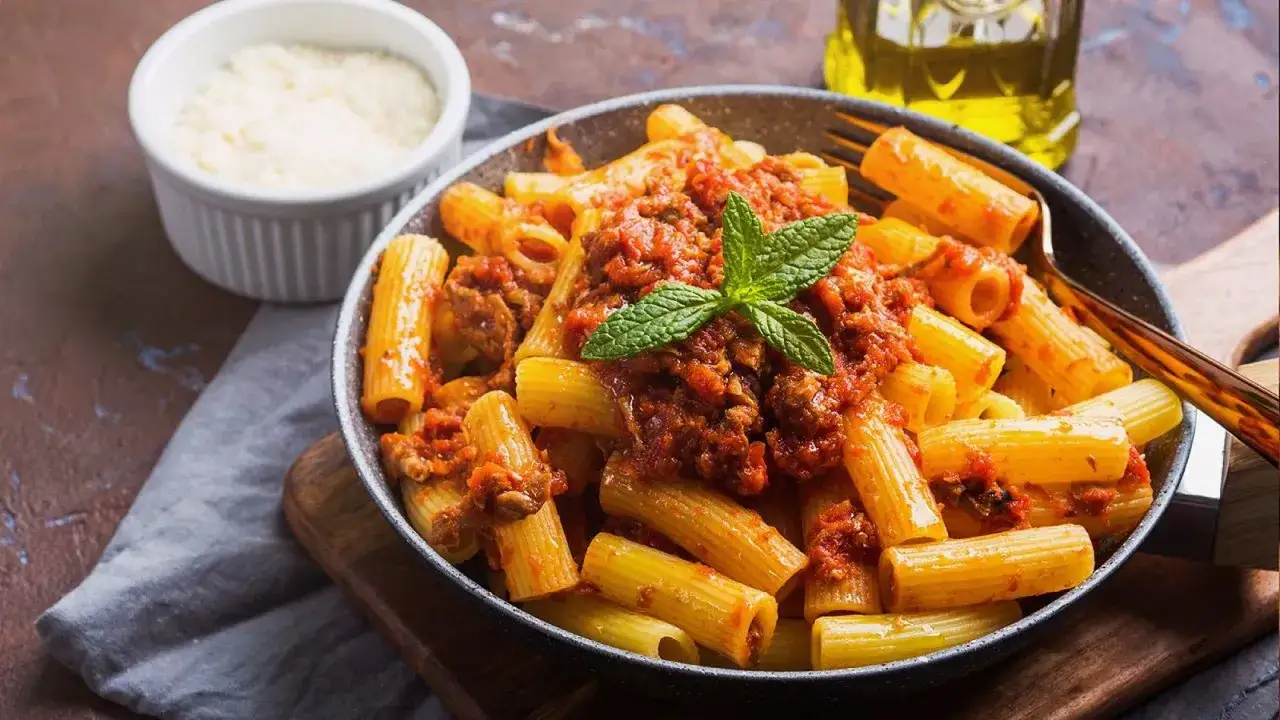 Macarrones con carne picada, cubiertos con salsa de tomate y adornados con menta. Un plato delicioso y reconfortante.