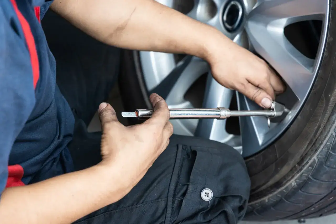 Mec&aacute;nico revisa la presi&oacute;n de un neum&aacute;tico de coche. Un clavo en rueda coche podr&iacute;a ser la causa de la fuga.