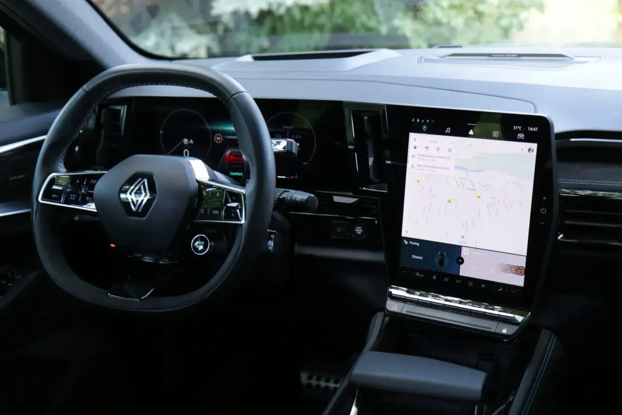 Wnętrze Renault Austral z ekranem nawigacji pokazującym trasę i kierownicą.