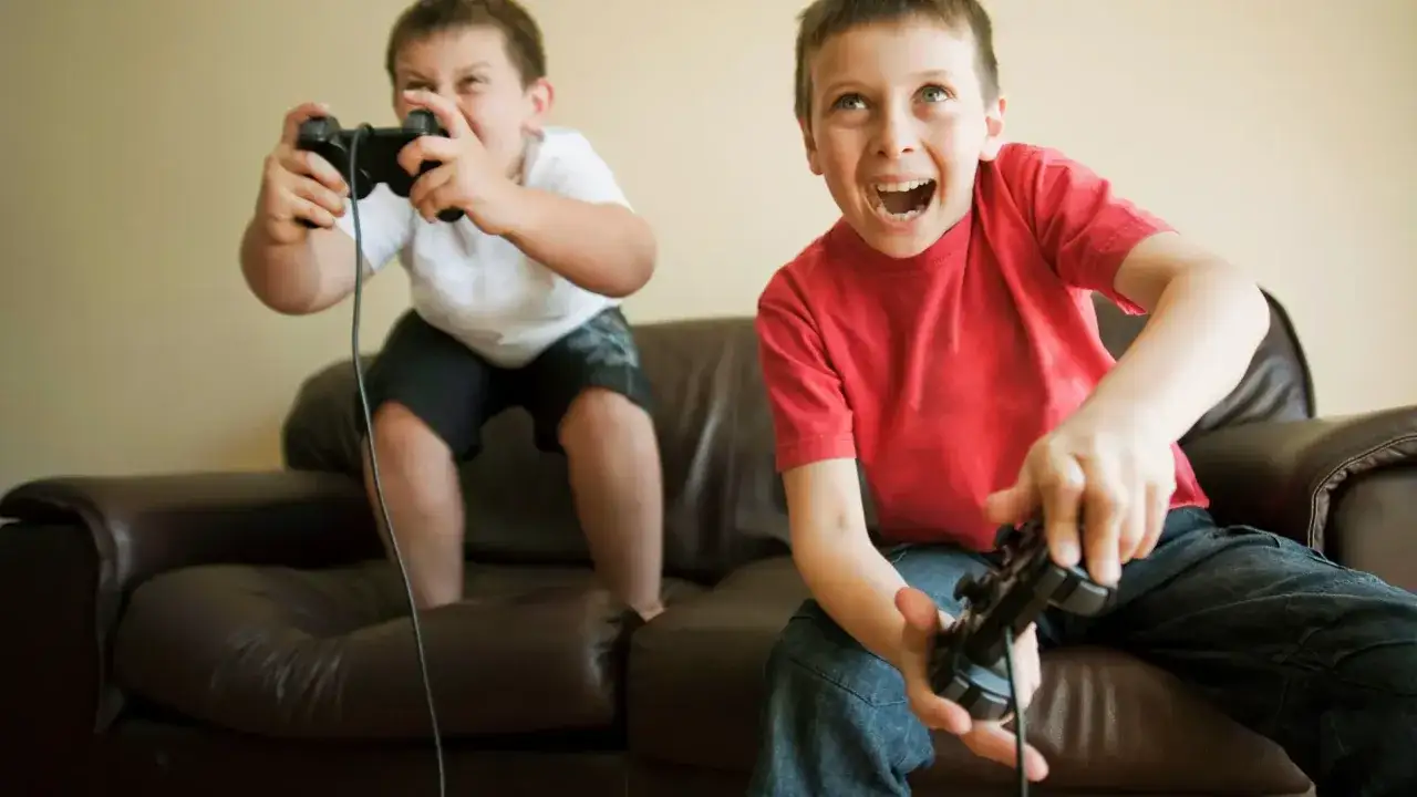 Dos niños emocionados jugando videojuegos en PS4. ¡Diversión garantizada con estos juegos ps4 para niños!