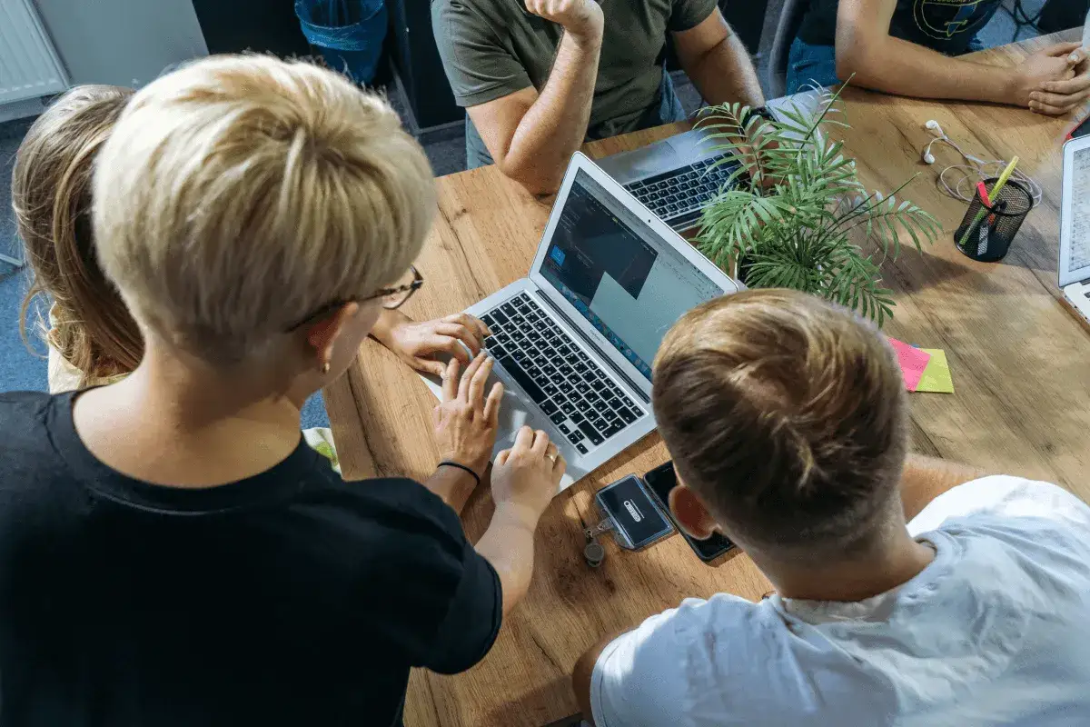 Zespół pracuje nad projektem, analityk IT analizuje dane na laptopie.
