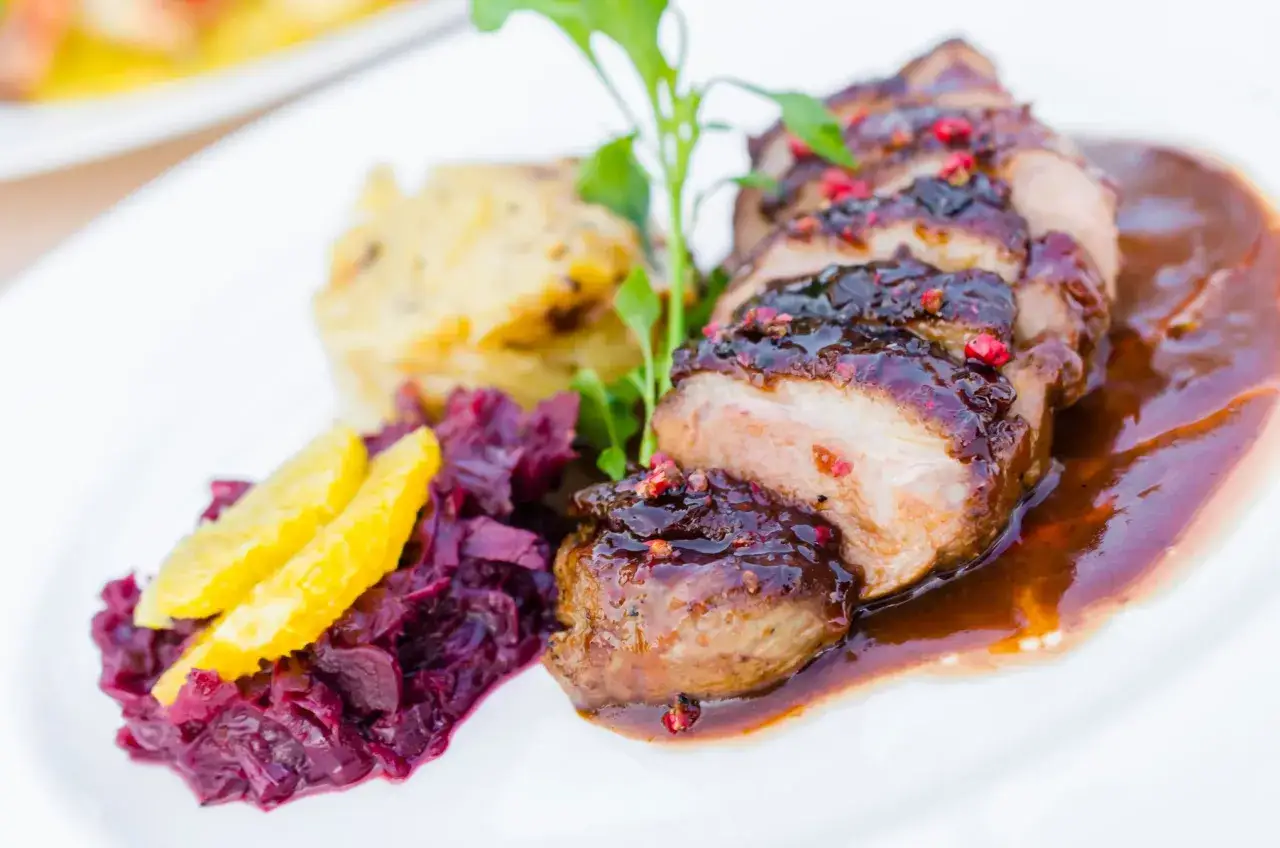 Soczysta pierś z kaczki w sosie, podana z purée ziemniaczanym i czerwoną kapustą z pomarańczą.