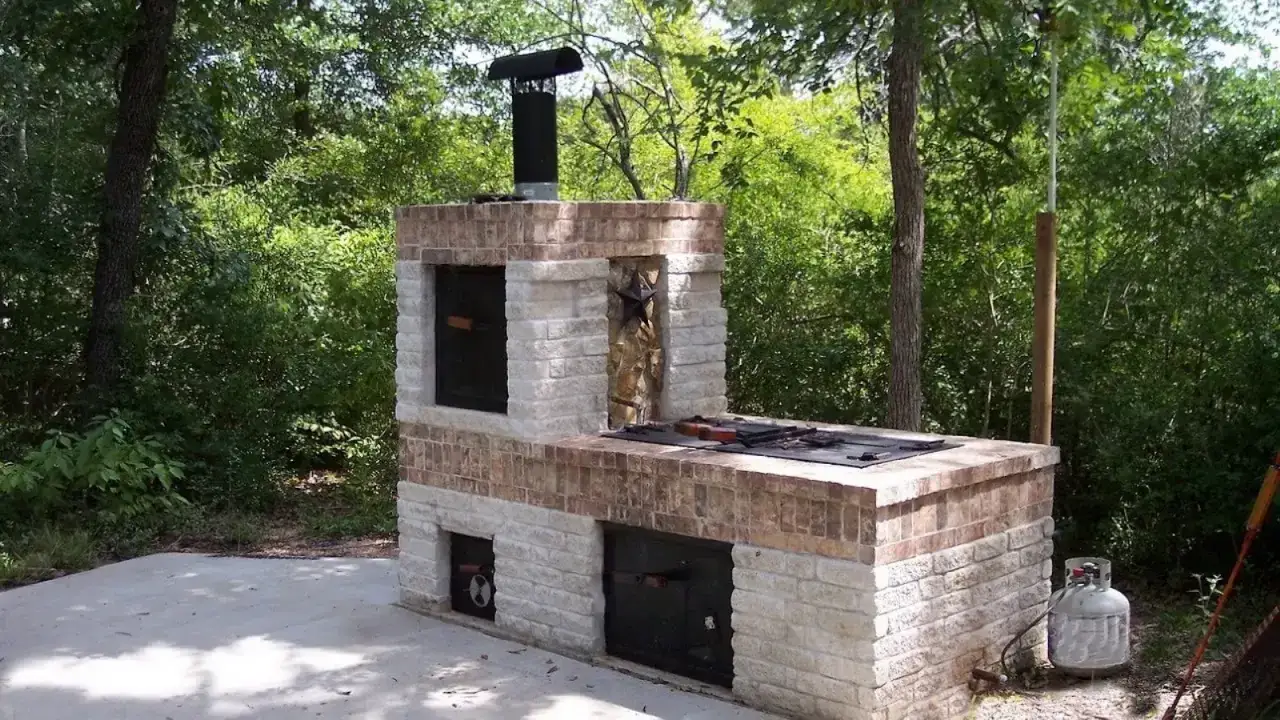 Un imponente barbecue fai da te in mattoni, con cappa e bombola del gas, pronto per grigliate all'aperto tra il verde.