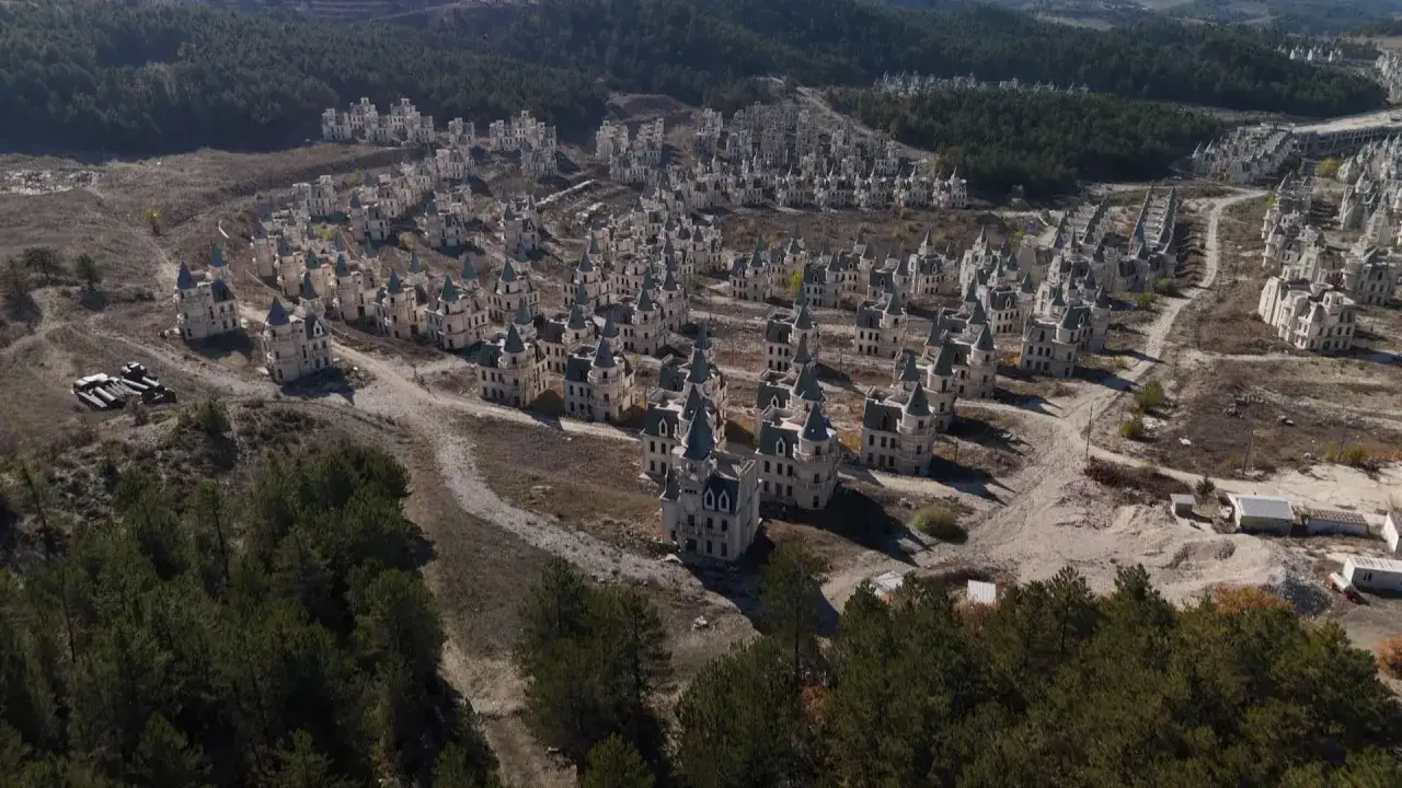 Un villaggio di castelli incompiuti, Burj Al Babas, si estende su una collina arida, circondato da foreste.