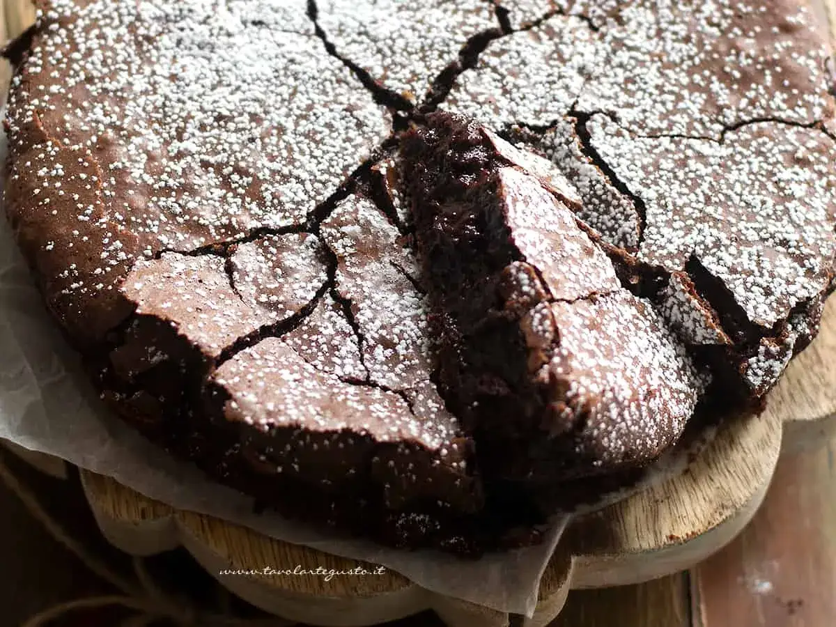 Una deliziosa torta al cioccolato senza glutine, con una crosta screpolata e cosparsa di zucchero a velo, pronta per essere gustata.