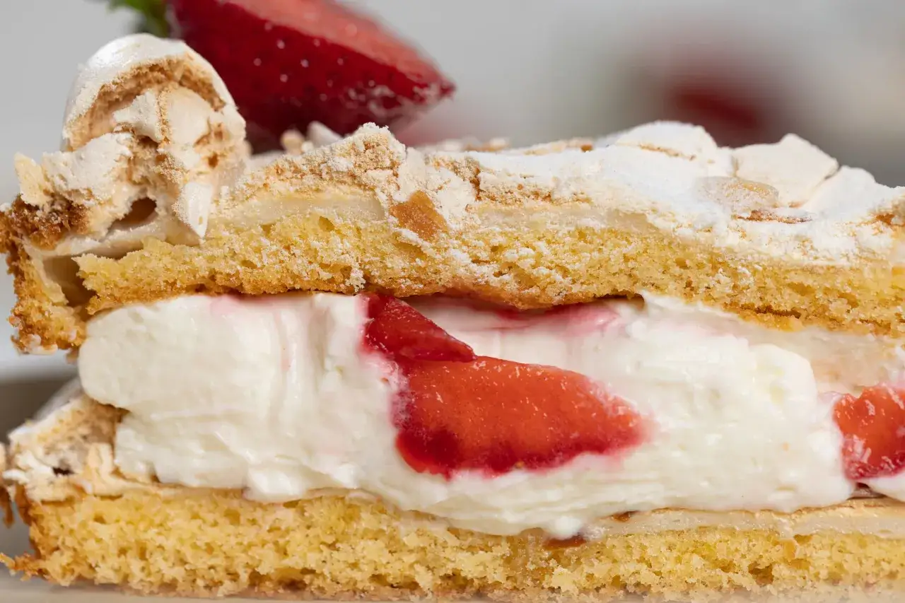 Ein Stück Erdbeer Baiser Torte mit sahniger Füllung und frischen Erdbeeren.