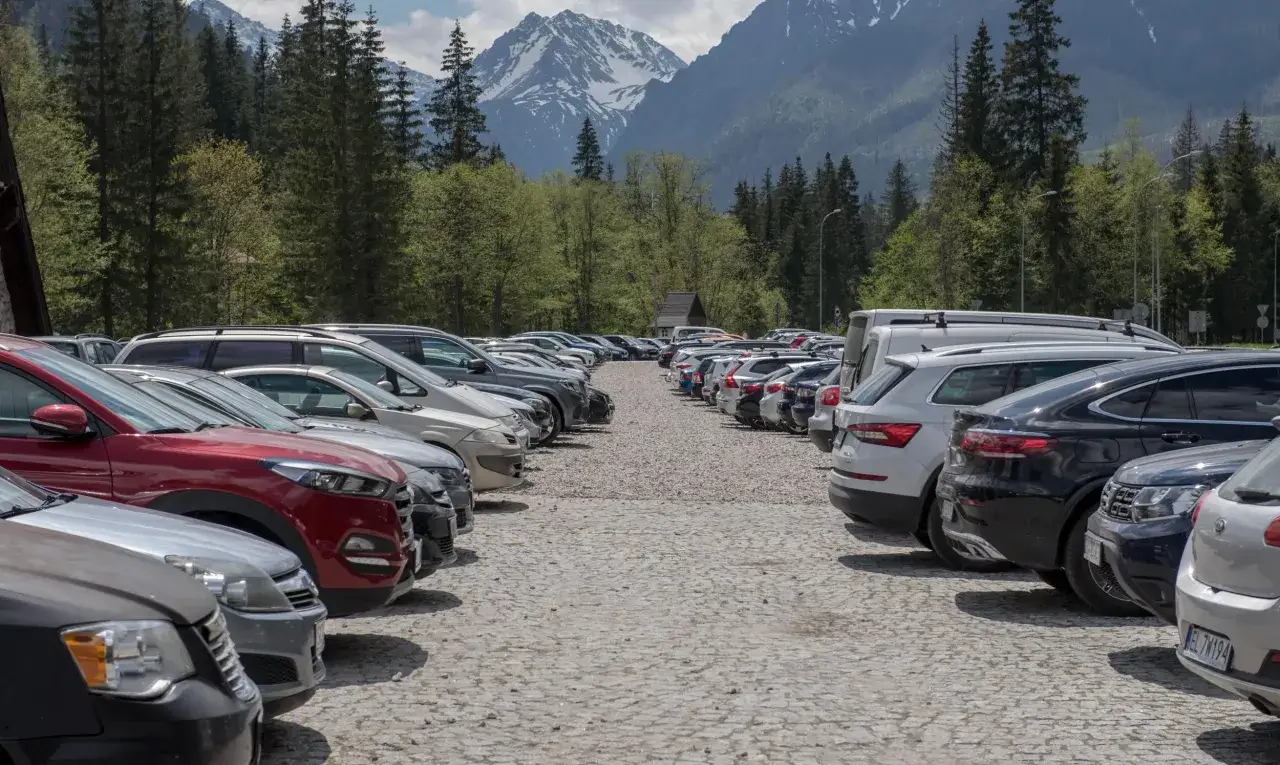 Parking przy Morskim Oku. Sprawdź morskie oko cennik, by zaplanować wycieczkę. Góry i lasy w tle.