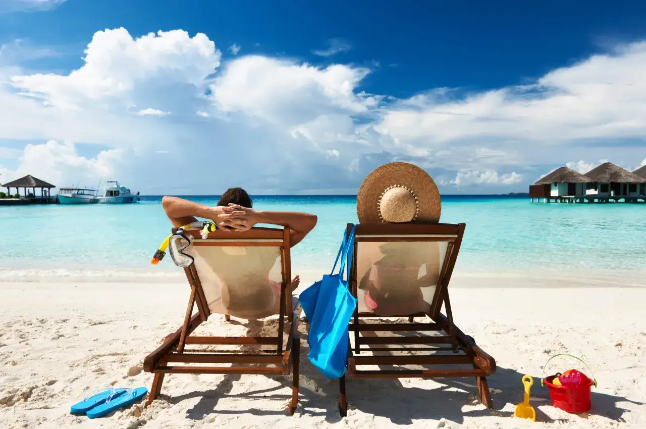 Couple se d&eacute;tend sur la plage, pr&ecirc;t &agrave; pr&eacute;parer la peau au soleil. Masque de plong&eacute;e, tuba et chapeau de paille &agrave; port&eacute;e de main.