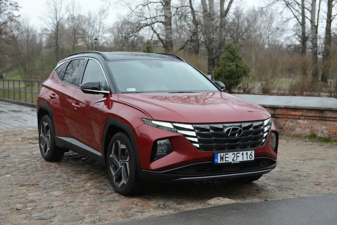 Czerwony Hyundai Tucson 1.6 benzyna 150KM na mokrej, brukowanej drodze. Zastanawiasz się, ile pali ten model?
