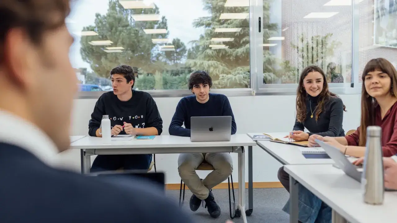 Estudiantes discuten estrategias de **marketing digital** en un aula.