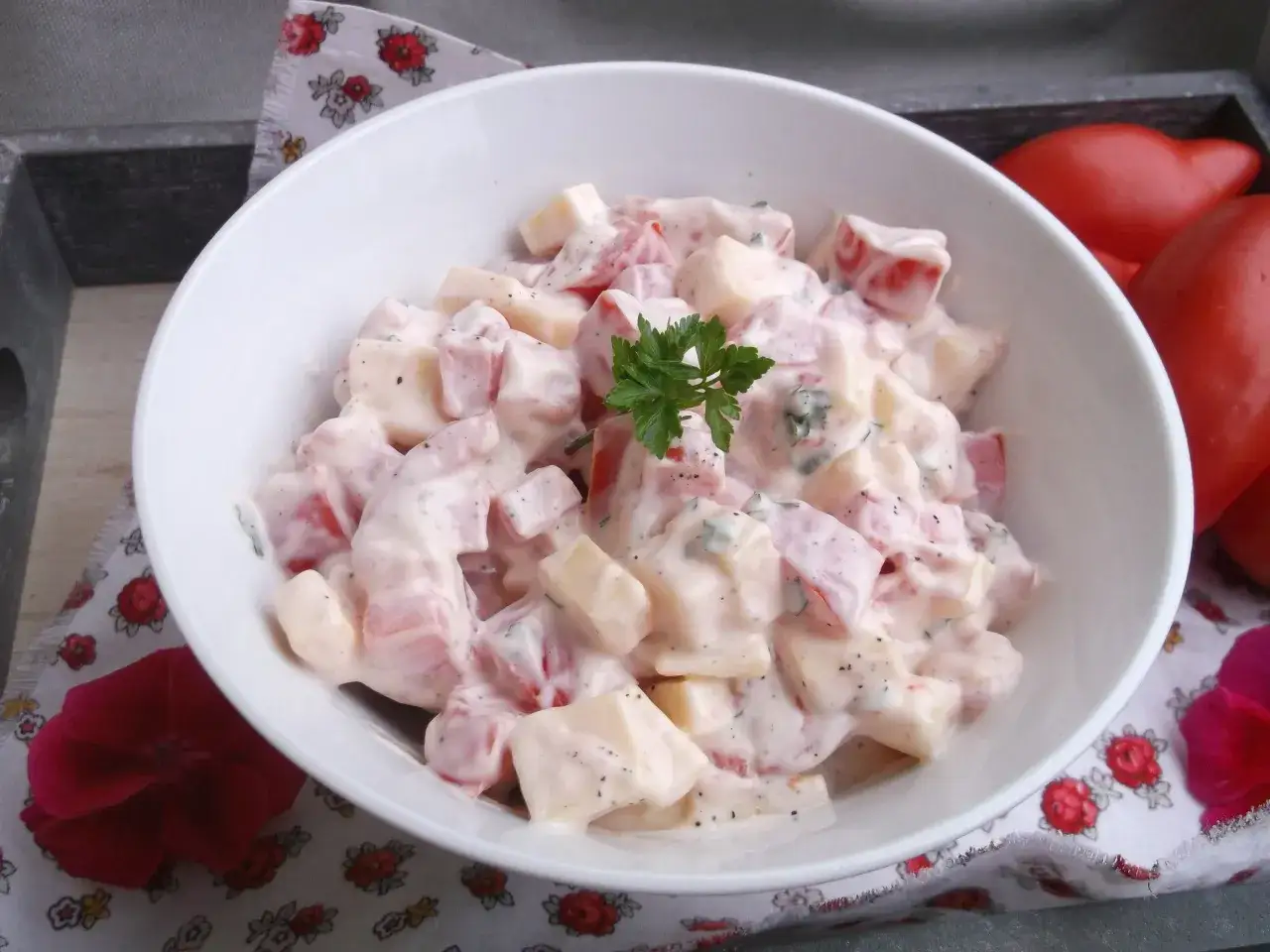 Pyszne pomidory pod pierzynką kremowego sosu, udekorowane natką pietruszki. Idealna sałatka na lato.