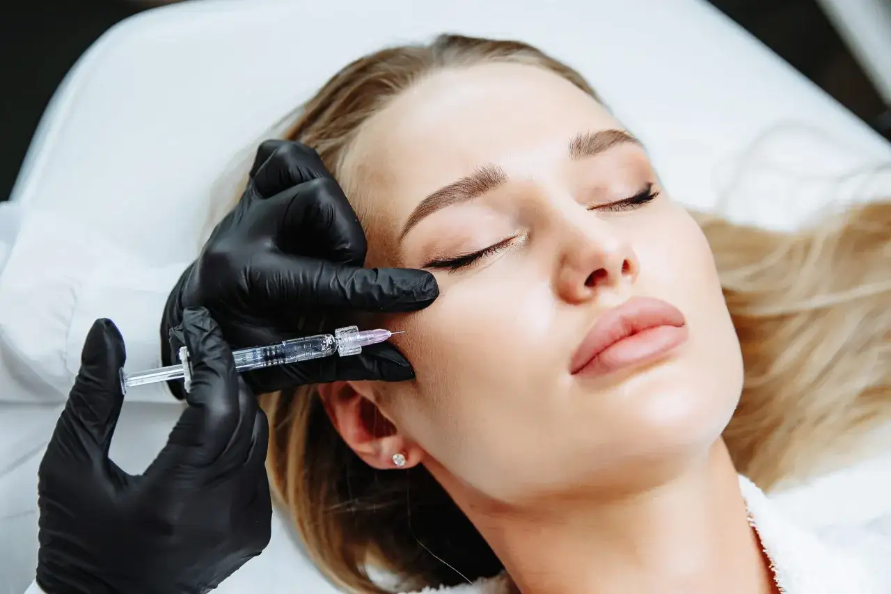Mano con guanto nero inietta una fiala sul viso di una donna. Trattamento di medicina estetica con esosomi viso per un aspetto più giovane.