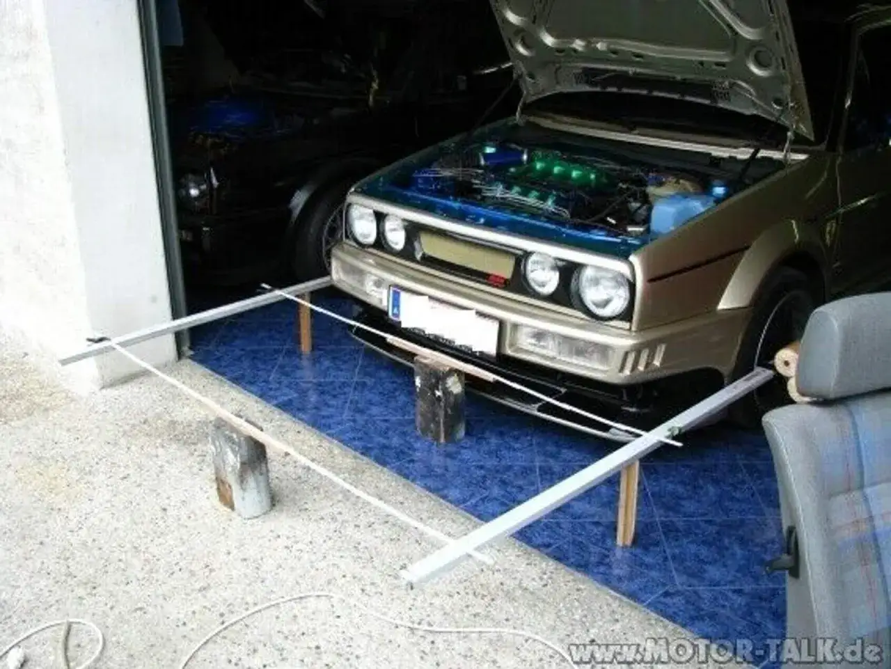 Selbstgemachte Achsvermessung: Ein Golf mit ge&ouml;ffneter Haube und selbstgebautem Messgestell vor dem Auto.