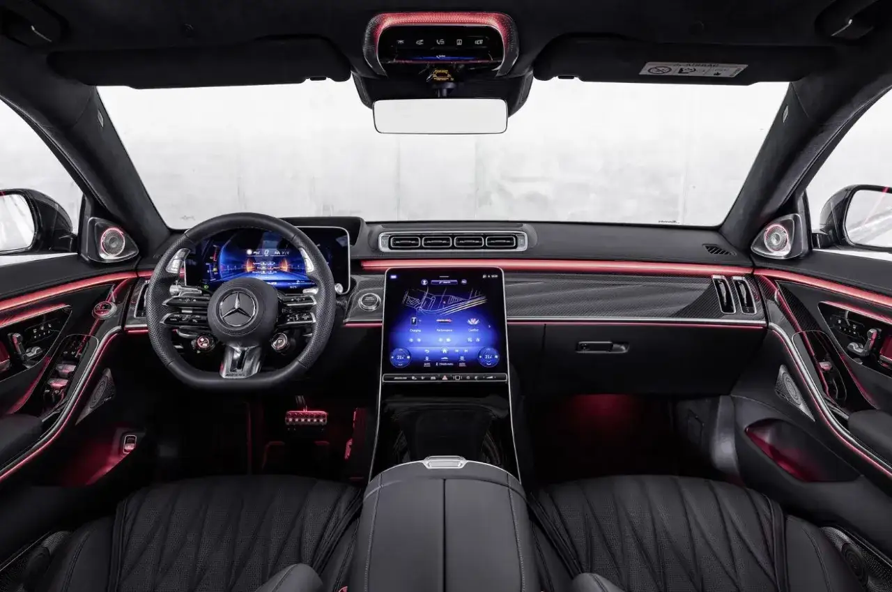 Wnętrze S 63 AMG Mercedes-Benz z czerwonym ambientowym oświetleniem, dużym ekranem dotykowym i cyfrowymi zegarami.