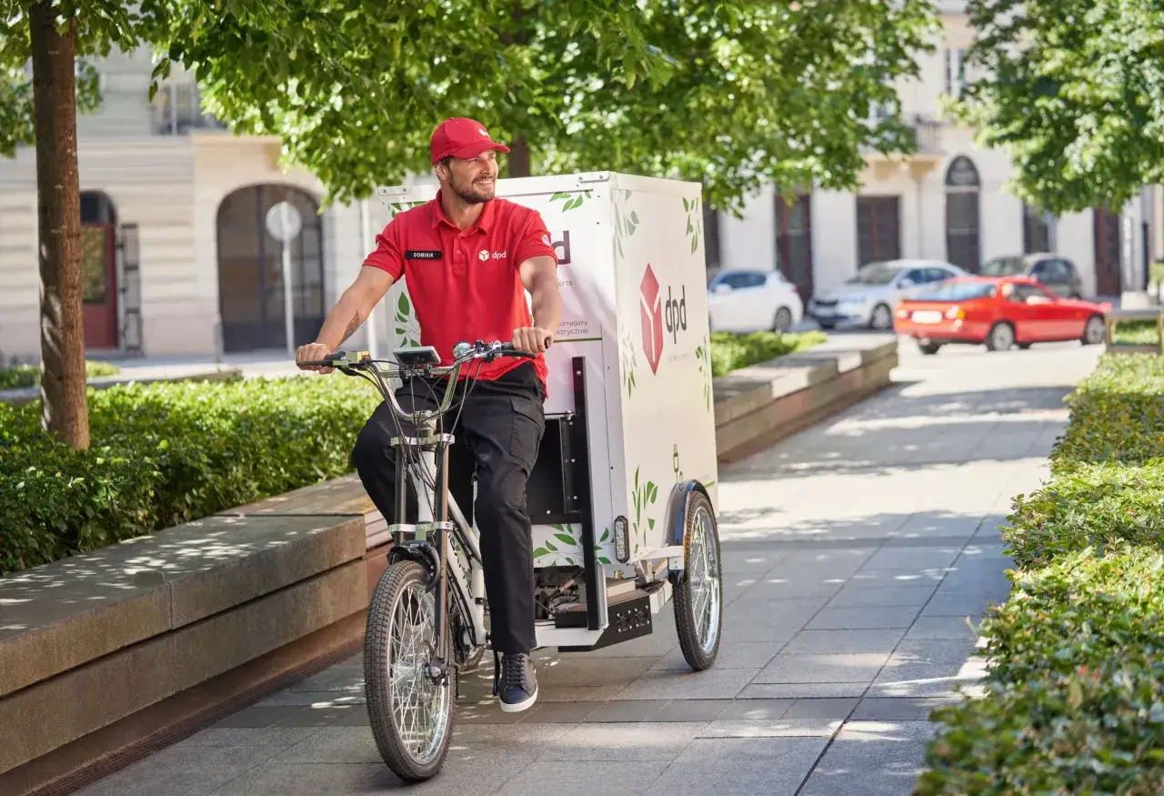 Kurier DPD na rowerze cargo dostarcza paczkę. Sprawdź, jaka jest dpd wysyłka roweru cena i wybierz ekologiczny transport.