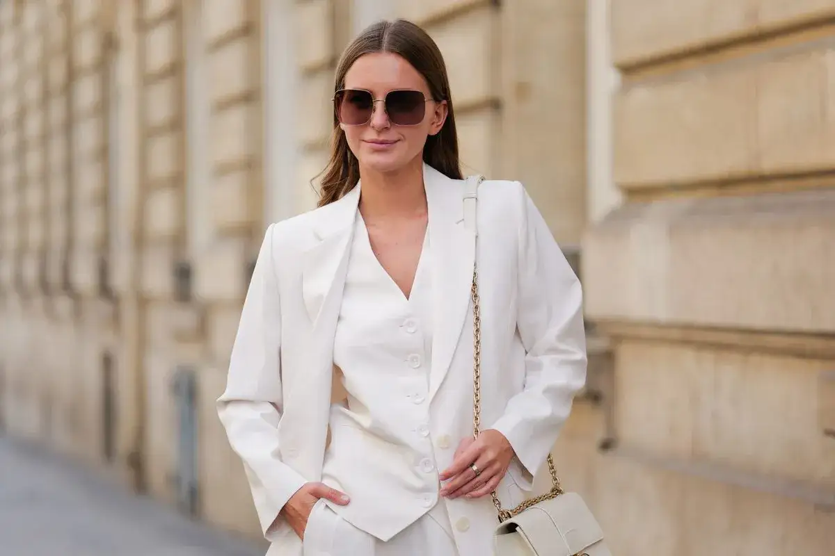 Kobieta w eleganckim, białym garniturze. Kolor ivory, czyli delikatna biel, podkreśla jej styl.