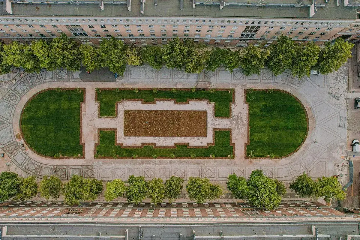 Nowa Huta co zobaczyć: geometryczny park z trawnikami i alejkami, otoczony socrealistyczną architekturą.