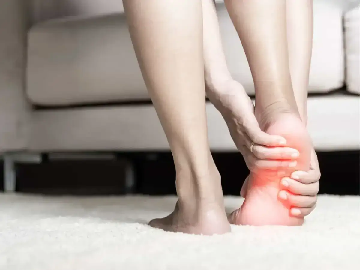 A person holds their heel, experiencing foot pain. This image illustrates the search for natural remedies for foot pain.