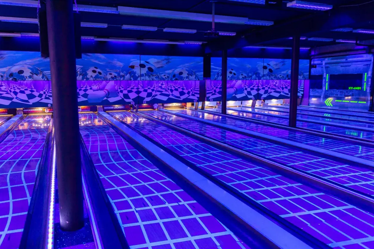 Leuchtende Bowlingbahnen in Wermelskirchen, unter blauem Licht und mit schachbrettartigen Mustern.