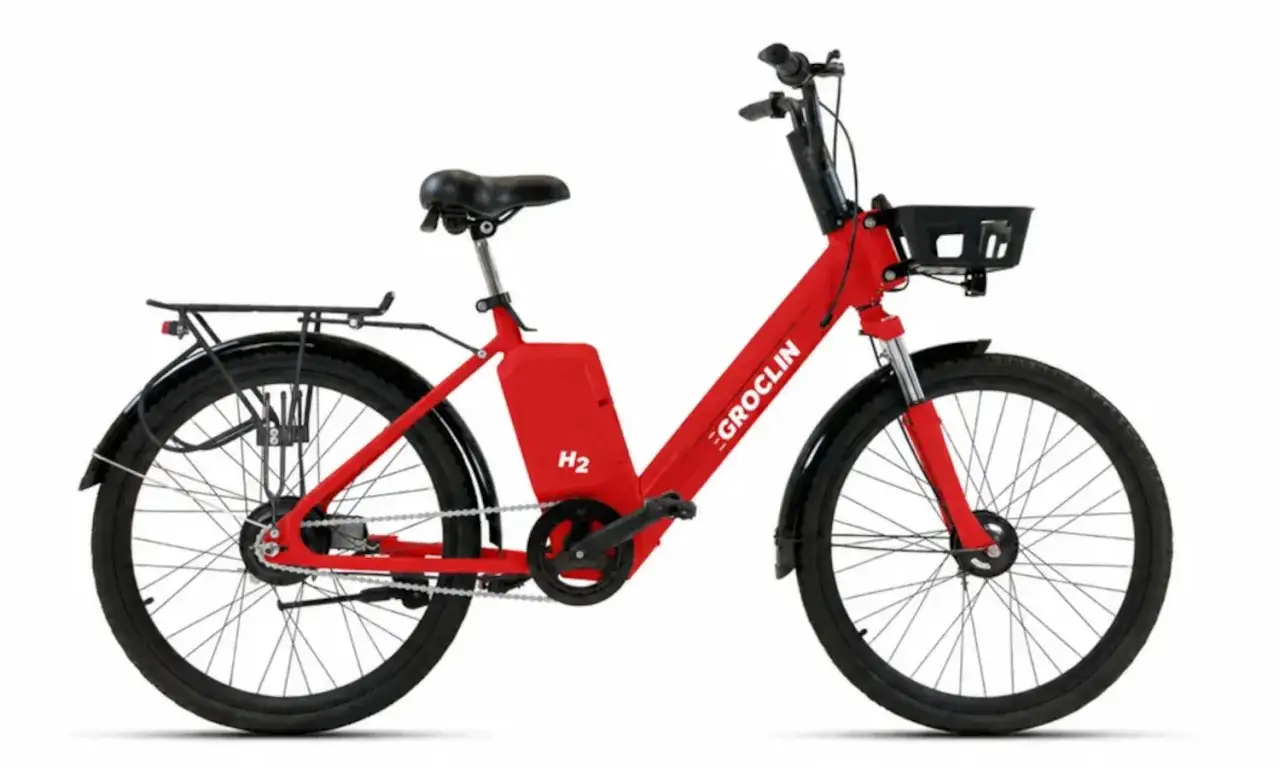 Czerwony rower elektryczny Groclin H2 z koszykiem z przodu i bagażnikiem z tyłu. Idealny do miejskich podróży.
