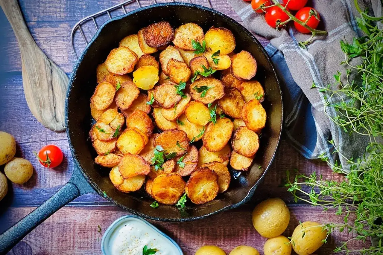 Goldbraune Bratkartoffeln im Gusseisenpfanne, garniert mit Petersilie. Ein einfaches Bratkartoffeln Rezept, das immer gelingt.