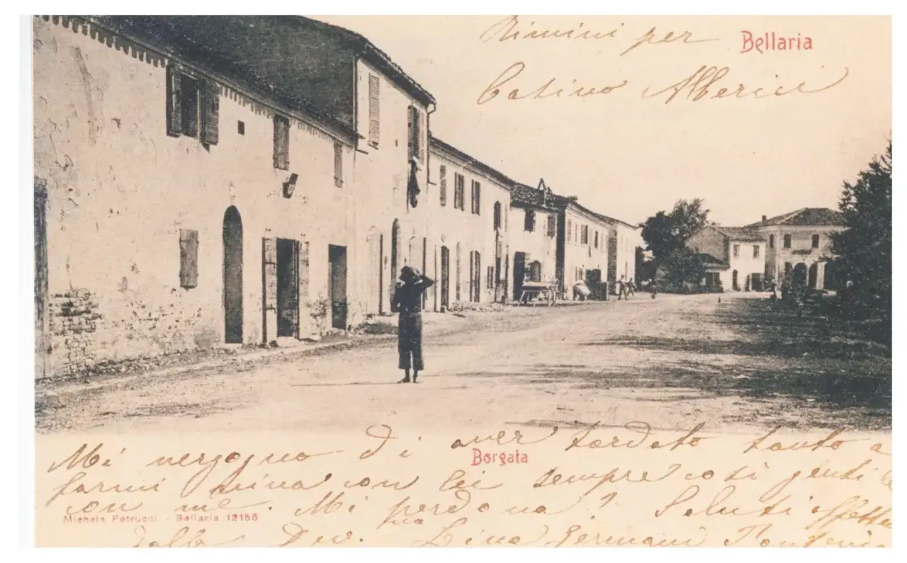 Antica strada di Bellaria, con case basse e un uomo di spalle. La scritta 
