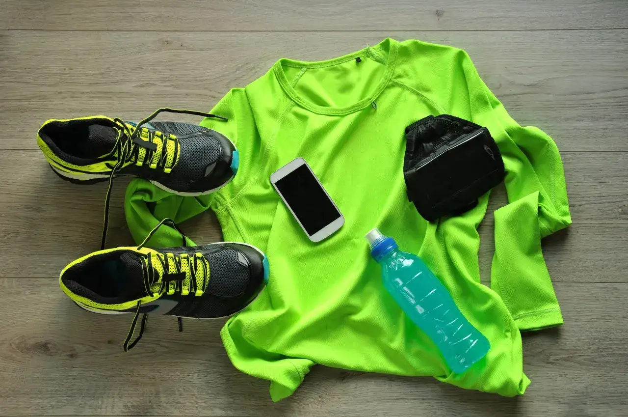 Buty do biegania, koszulka, telefon, napój i opaska na ramię – wszystko, co potrzebne, by jak przygotować się do maratonu.