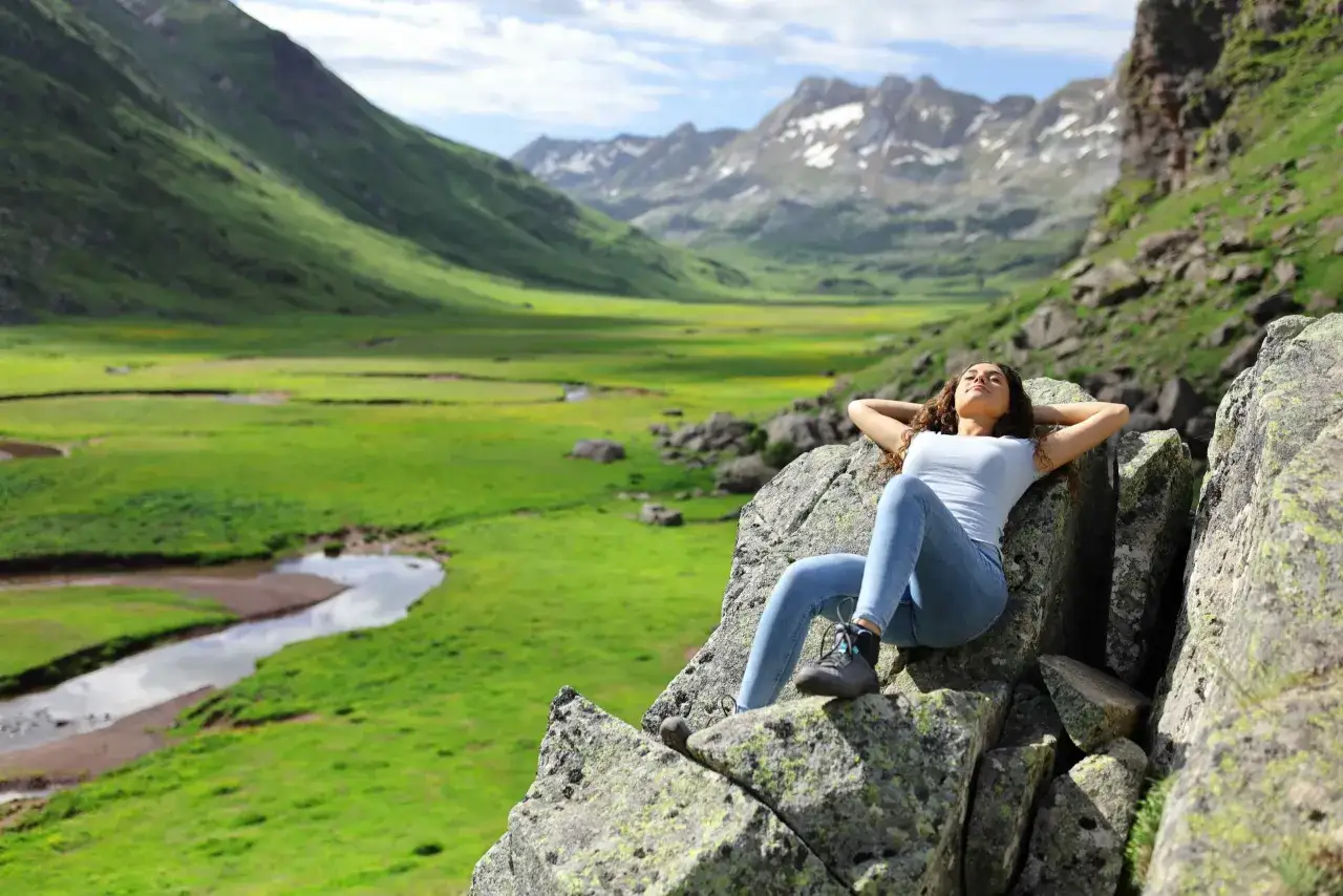 Joven disfrutando de la vista en las monta&ntilde;as, un paisaje perfecto para viajes inolvidables para adolescentes.