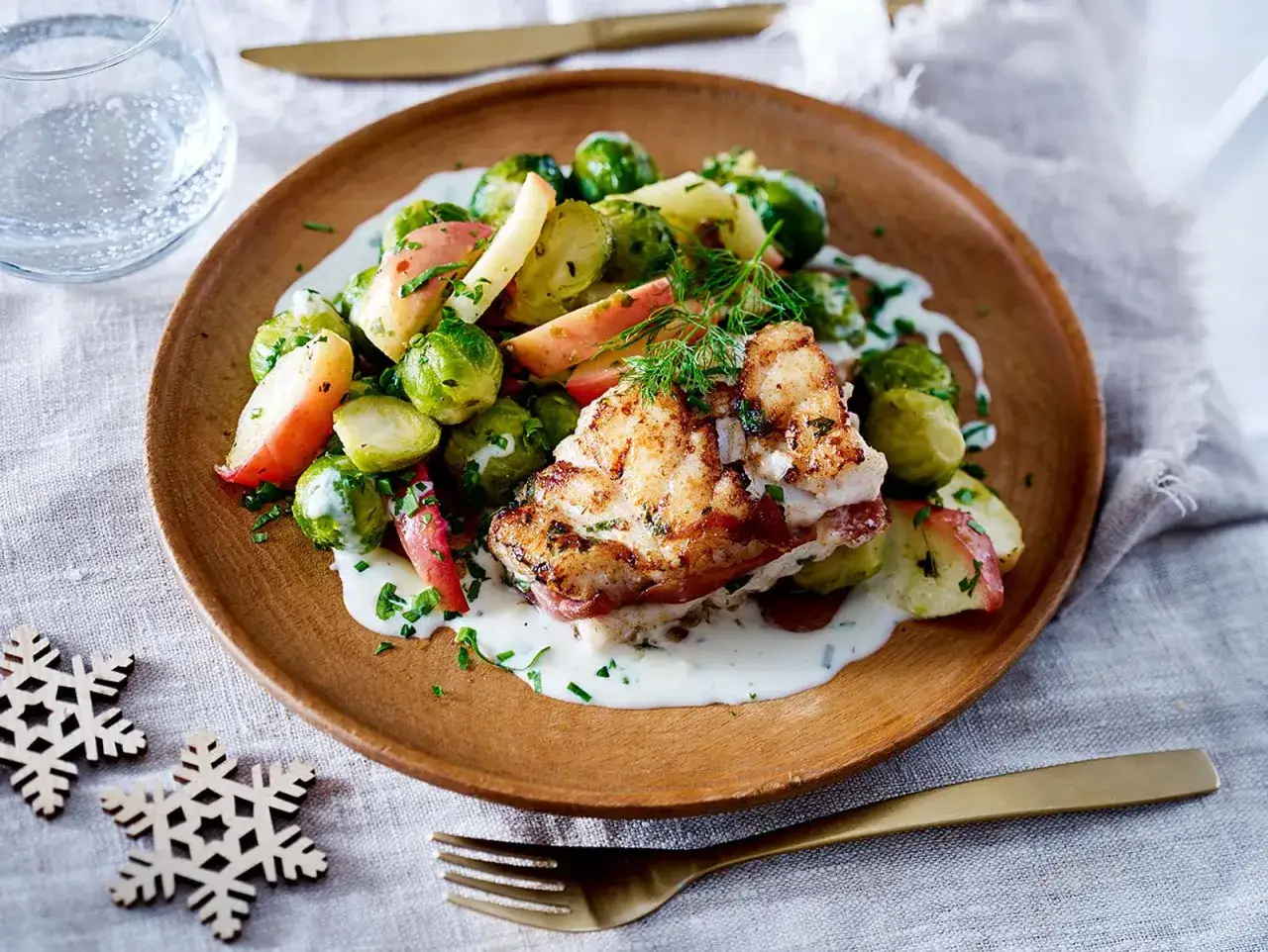 Gebratener Fisch mit Rosenkohl und Apfelspalten auf cremiger Sauce, ein festliches Gericht für Fischgerichte Weihnachten.