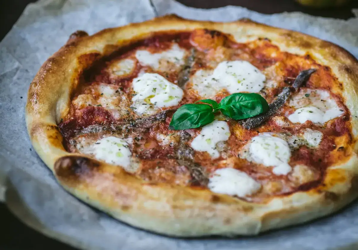 Pyszna pizza z anchois, mozzarellą i bazylią. Jeden z wielu pysznych rodzajów pizzy, idealna na każdą okazję.