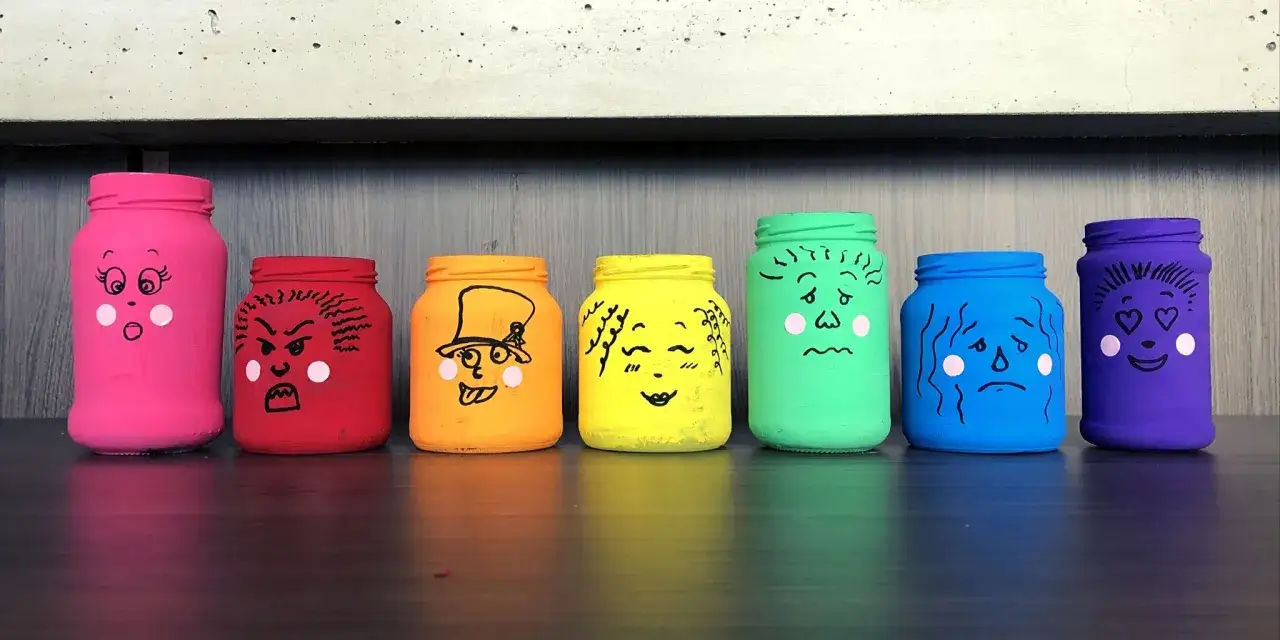 Un tarro de las emociones para niños, pintado de colores y con caras que expresan diferentes sentimientos: sorpresa, enfado, alegría, amor, tristeza.